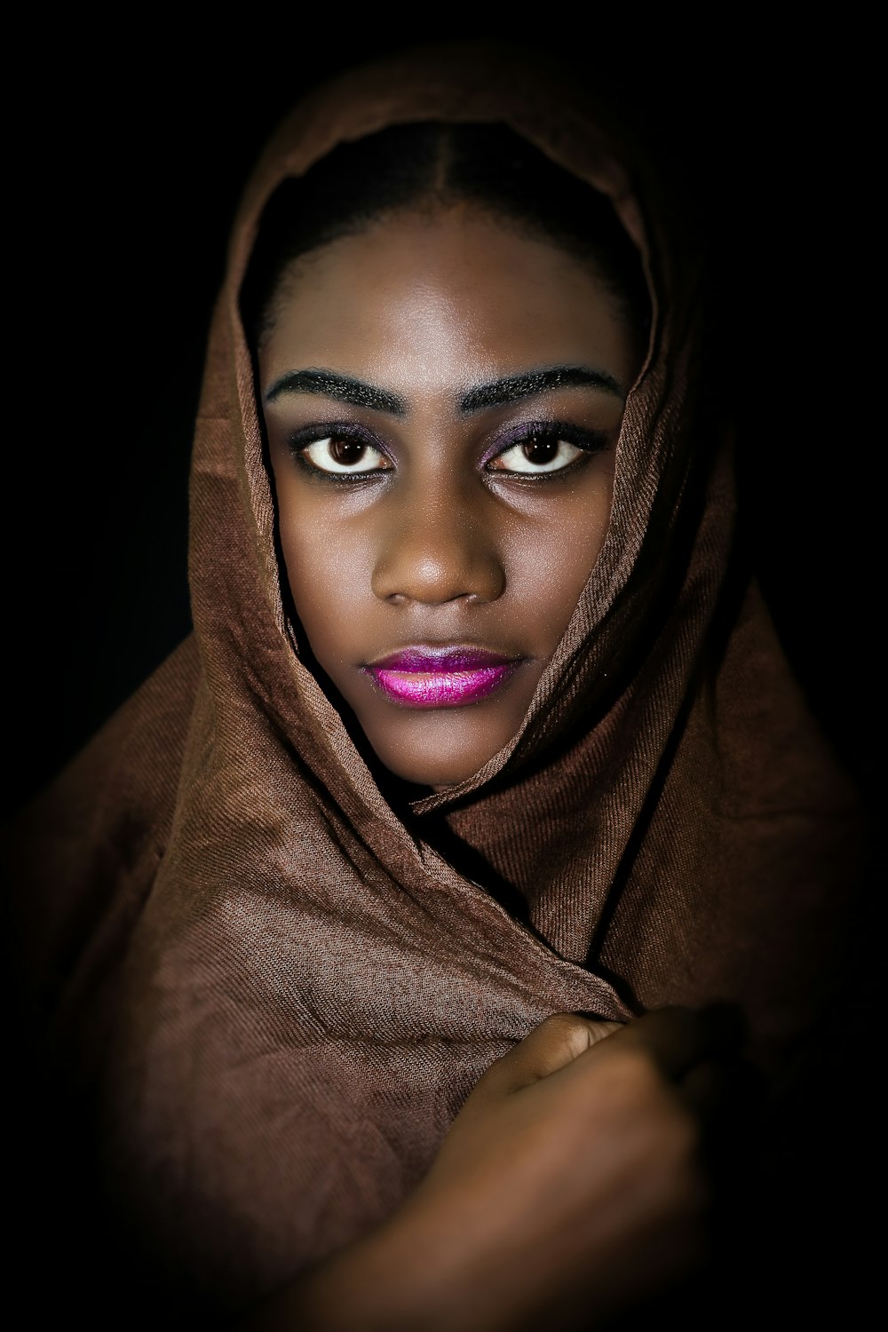 a woman wearing a brown shawl and pink lipstick