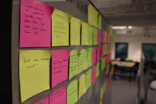 a bulletin board covered in sticky notes in an office