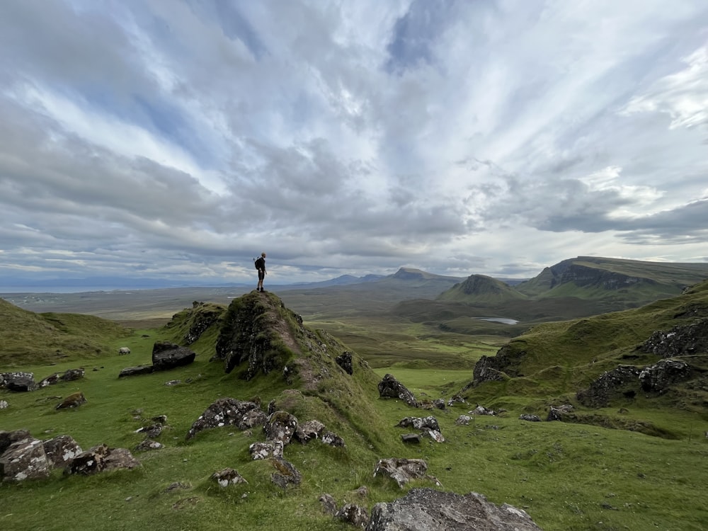 uma pessoa em pé no topo de uma colina coberta de grama
