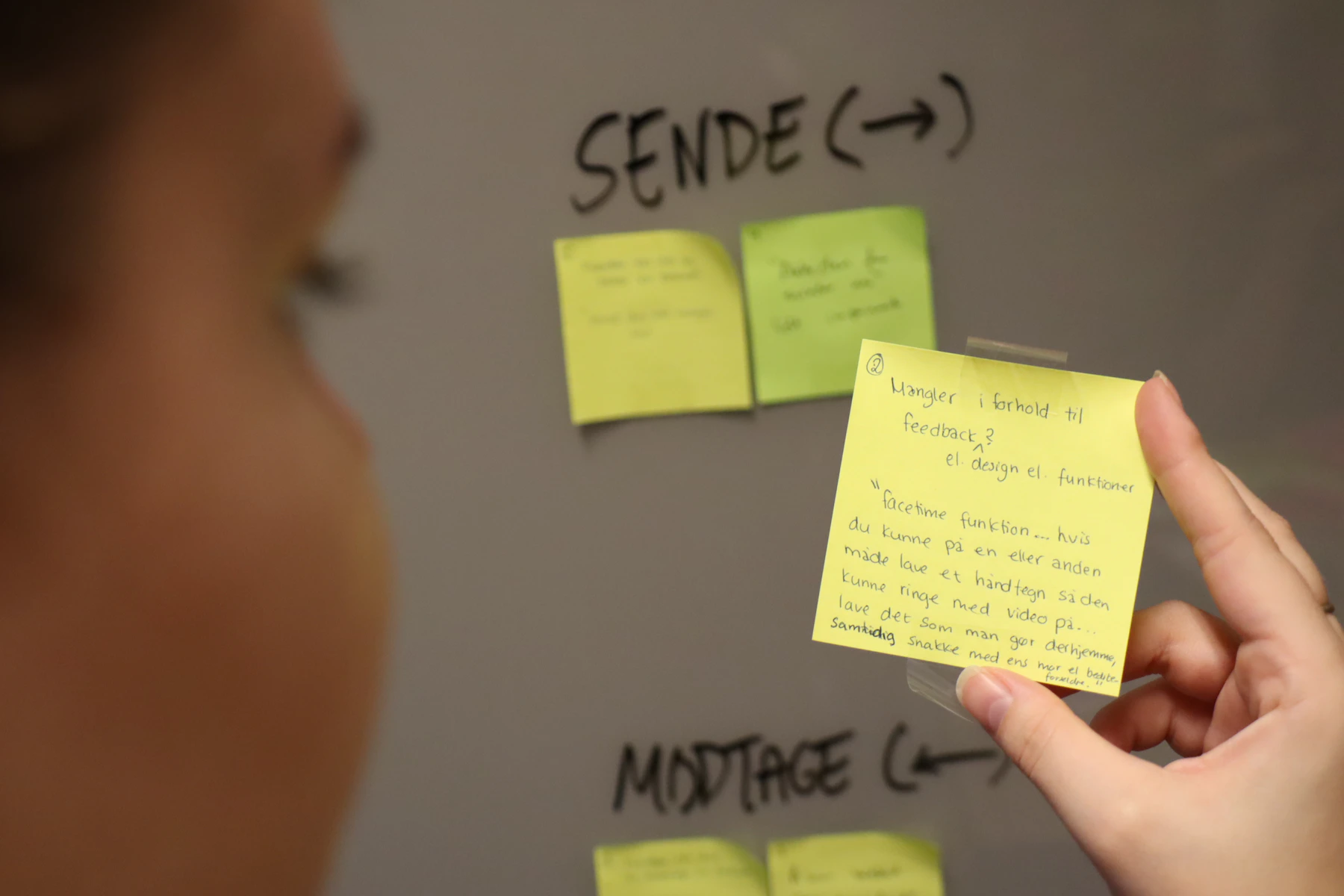 UX researcher working with an affinity wall of sticky notes during evidence synthesis