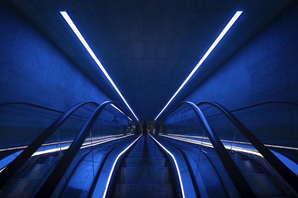 an escalator in a subway station with blue lighting