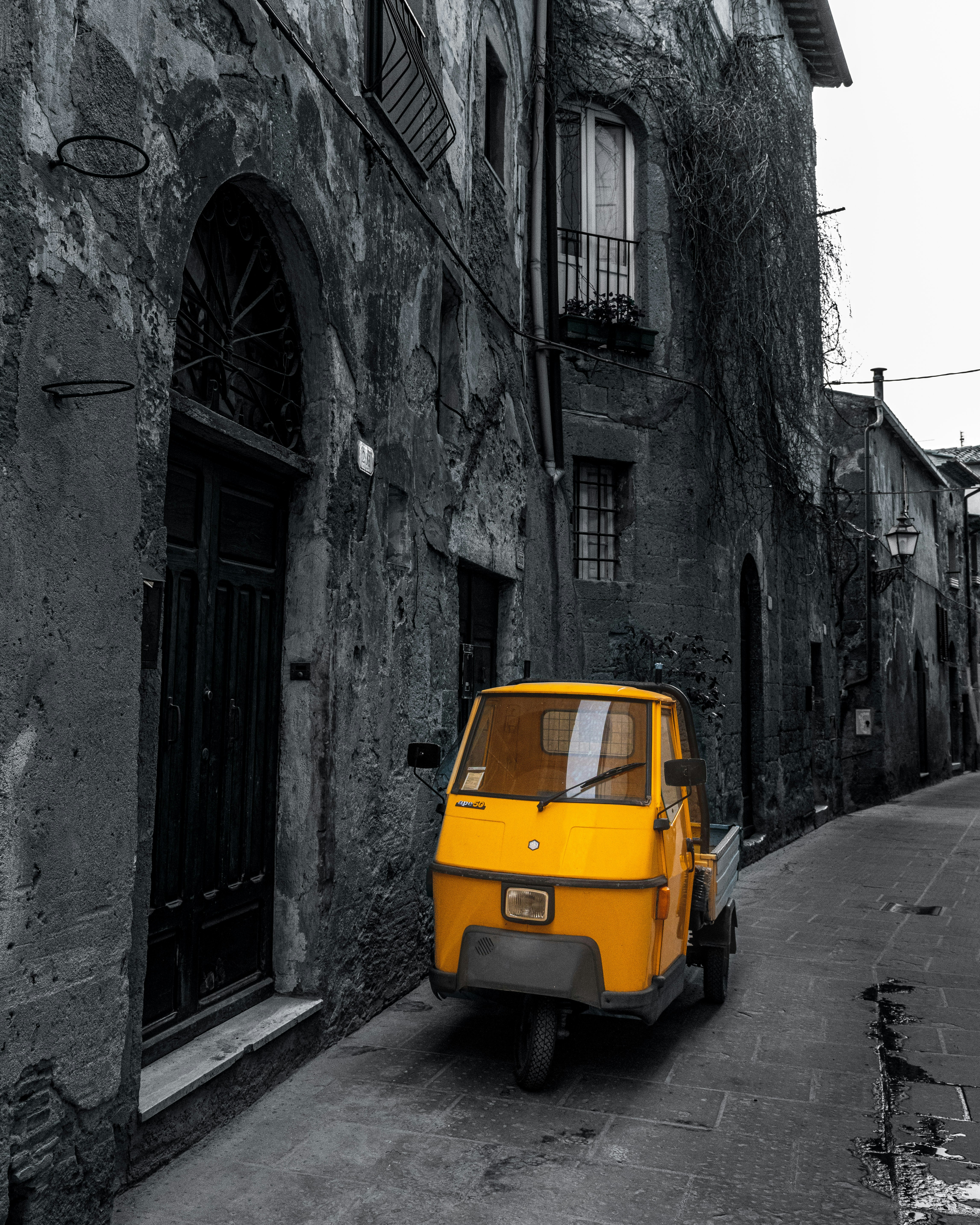 A small yellow car parked on the side of a street photo – Free City ...