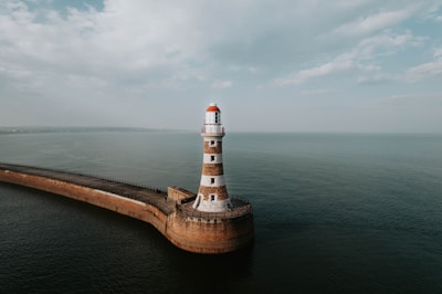 an aerial view of a lighthouse in the middle of the ocean