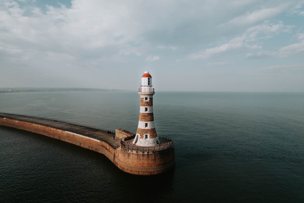 an aerial view of a lighthouse in the middle of the ocean