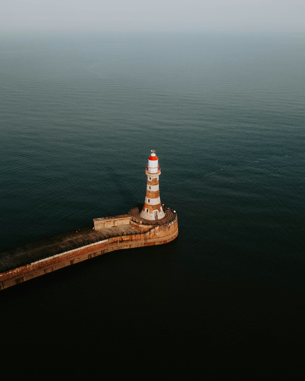 an aerial view of a light house in the middle of the ocean