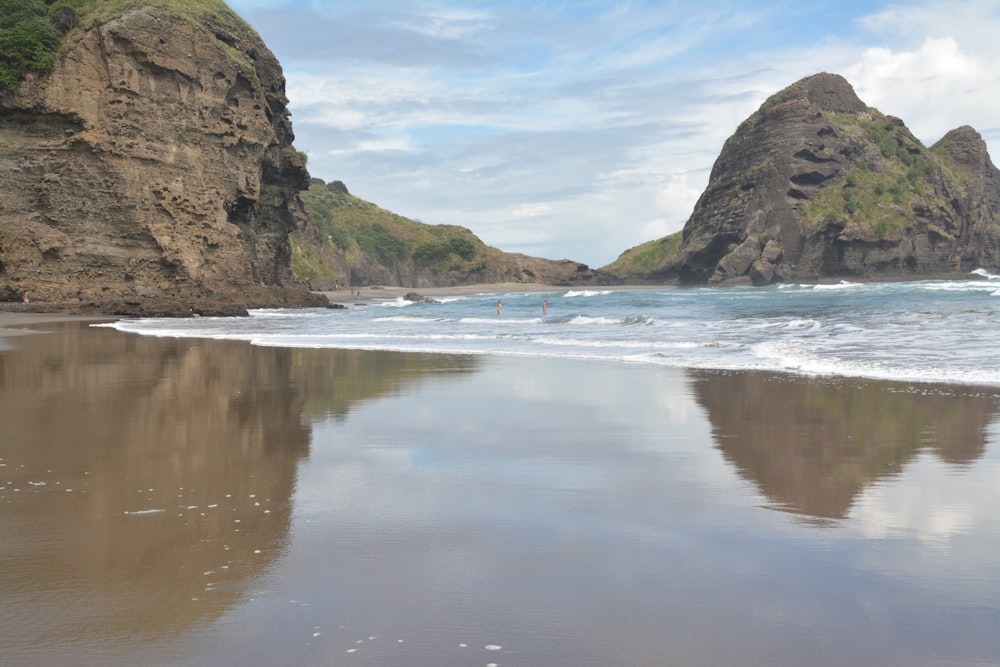 a sandy beach with a rock formation in the background