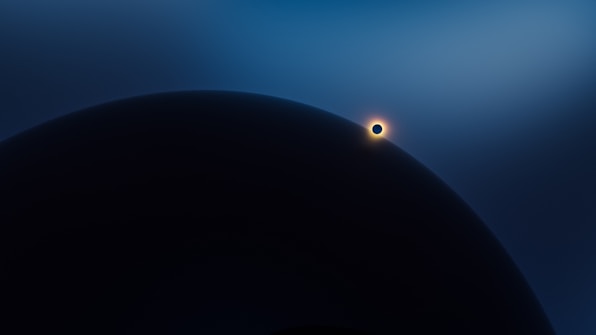 A large celestial body is partially obscured by shadow in the foreground, with a smaller, illuminated body positioned nearby, emitting a halo of light against a gradient blue sky.