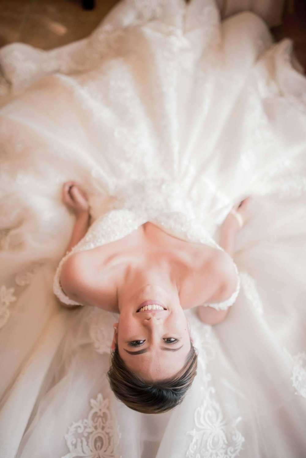 a woman in a wedding dress laying on the floor