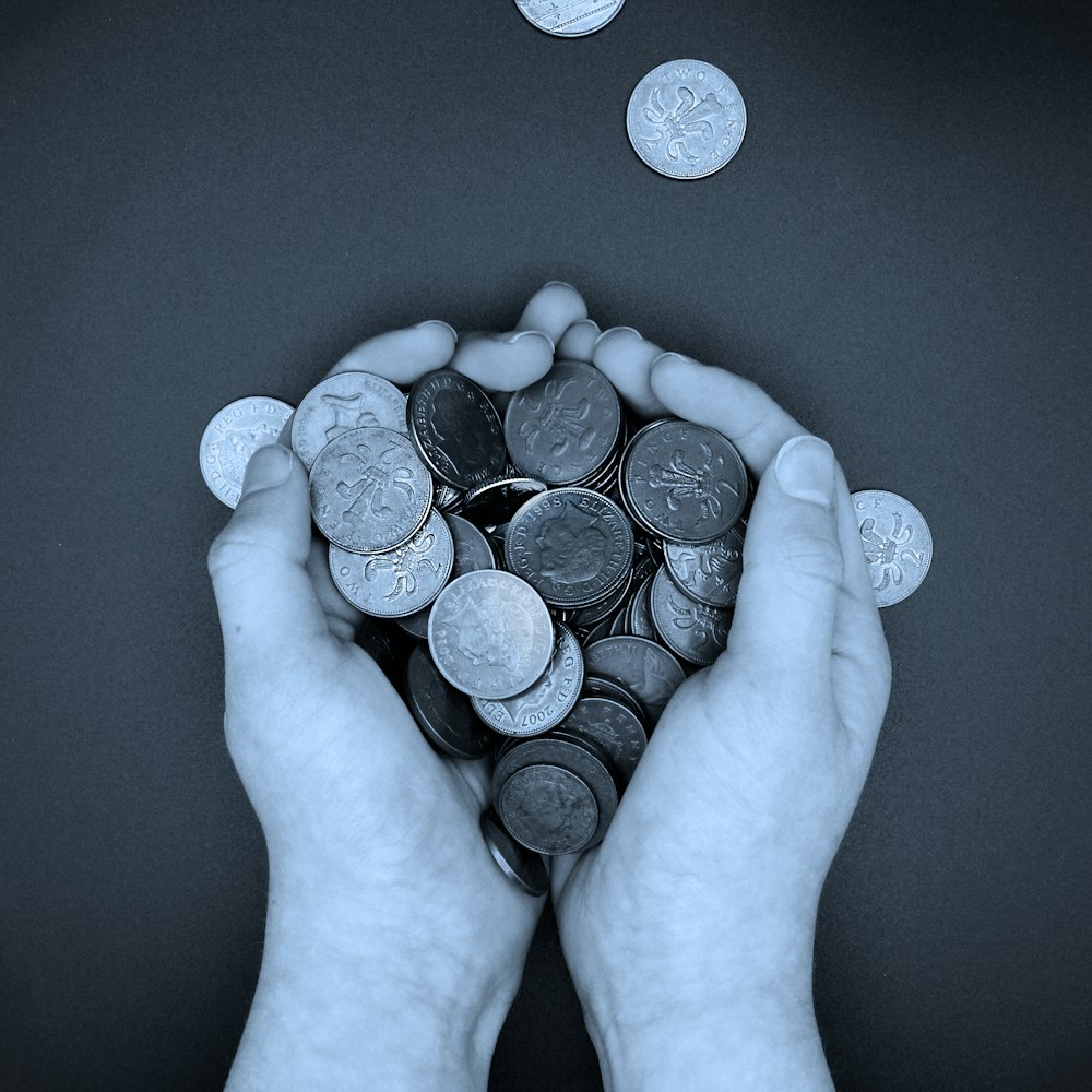 uma pessoa segurando um monte de moedas em suas mãos