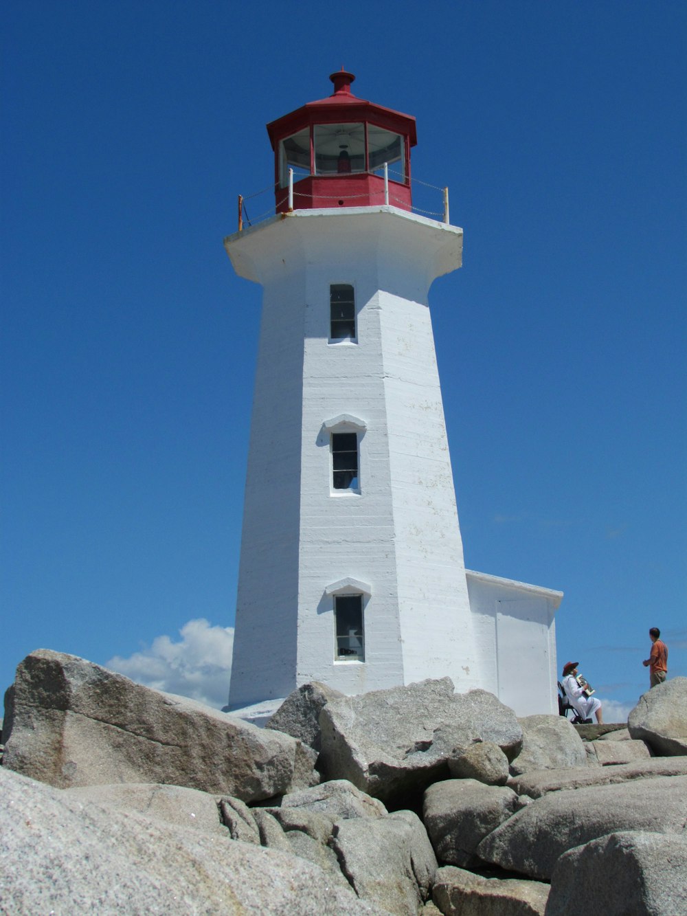 a white and red light house sitting on top of a rocky hill