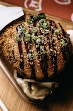 A vibrant plate of golden takoyaki balls drizzled with sauce and sprinkled with bonito flakes.