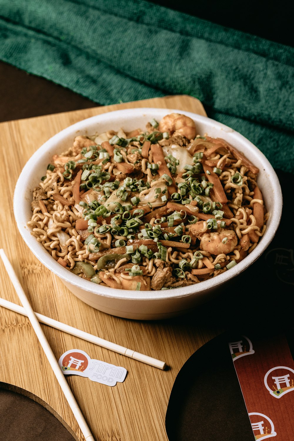 a bowl of noodles and chopsticks on a cutting board