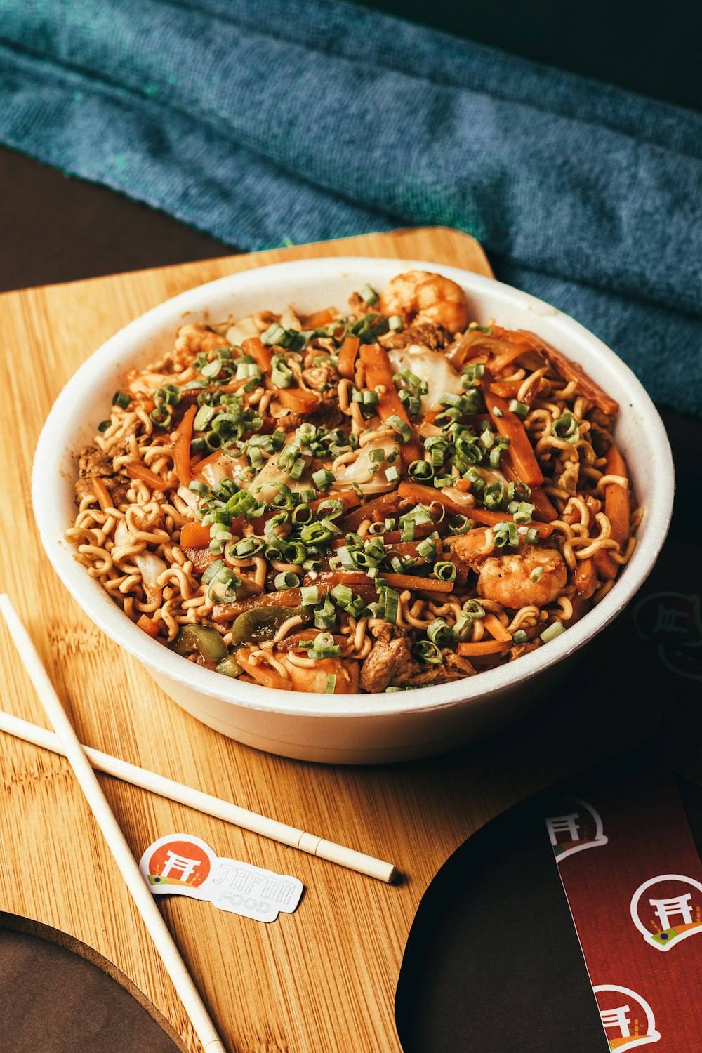 a bowl of noodles with vegetables and chopsticks