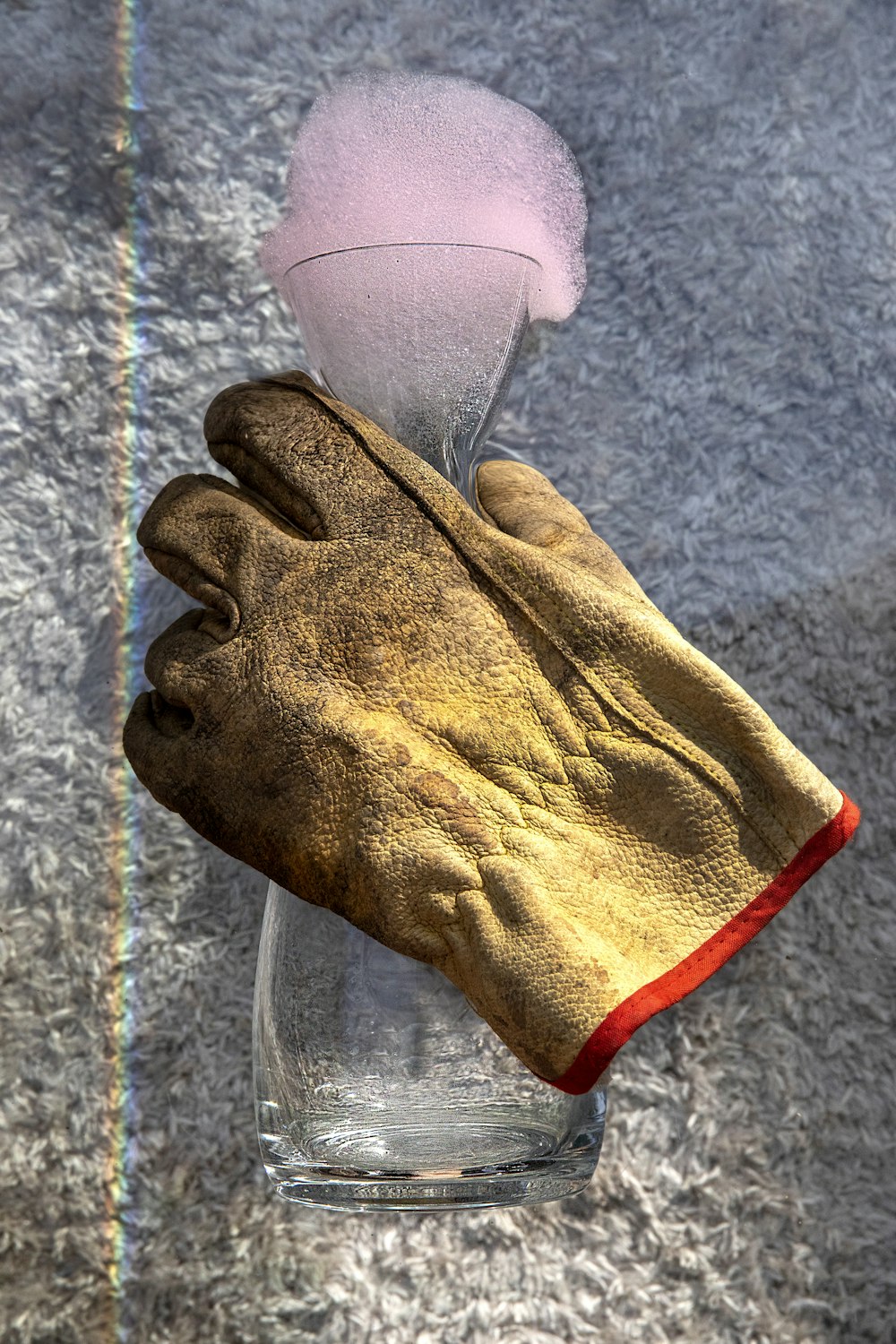 a pair of gloves sitting on top of a glass vase