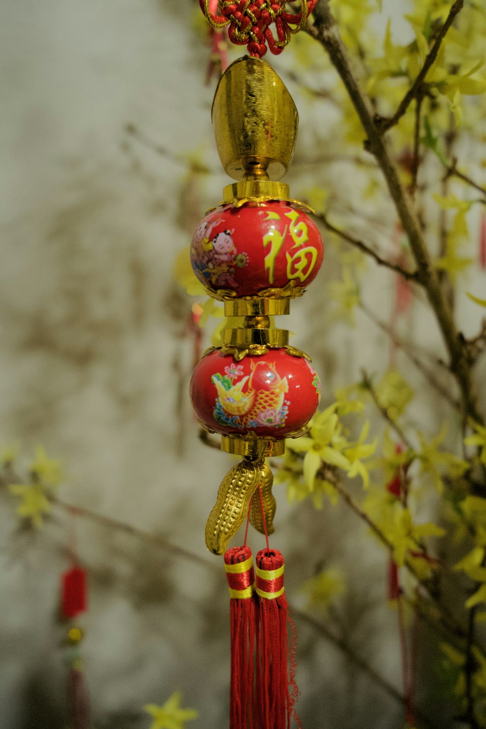 a red and gold decoration hanging from a tree