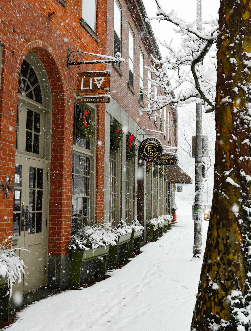 a snow covered street with a red brick building
