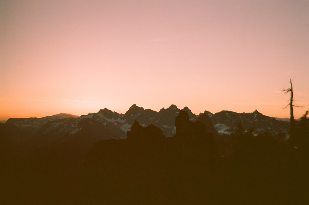 the sun is setting over a mountain range