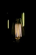 An illuminated Edison-style light bulb with visible filaments glowing warmly against a dark background.
