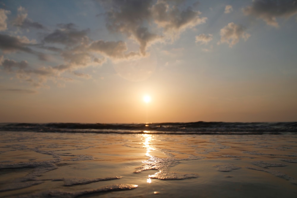 the sun is setting over the water at the beach