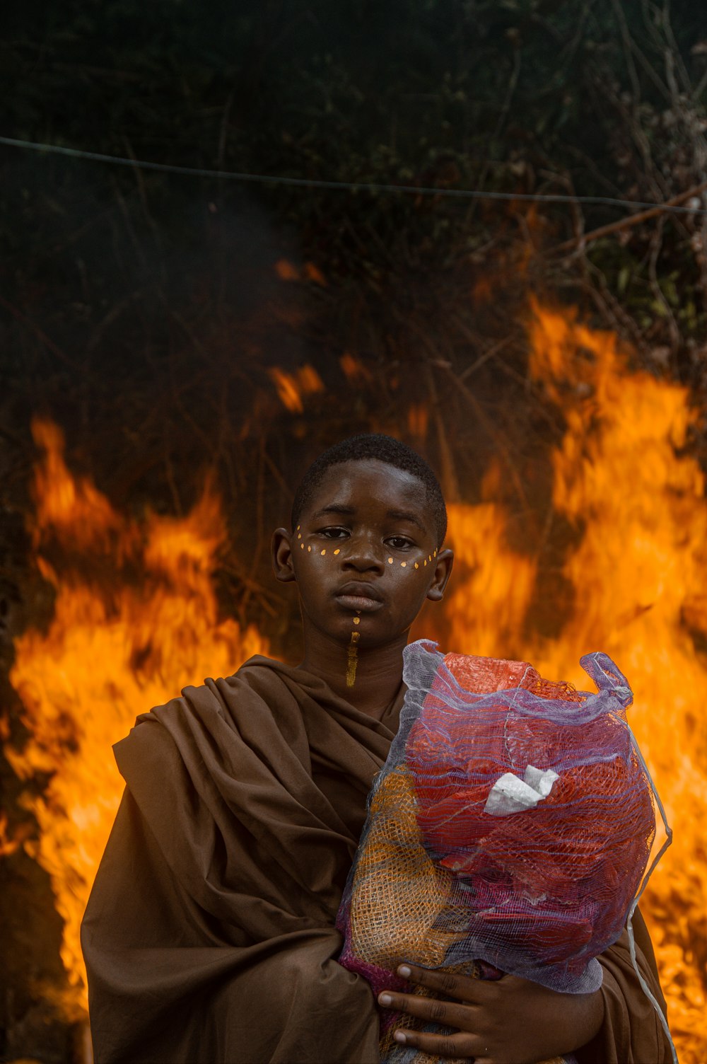 a man standing in front of a fire holding a bag