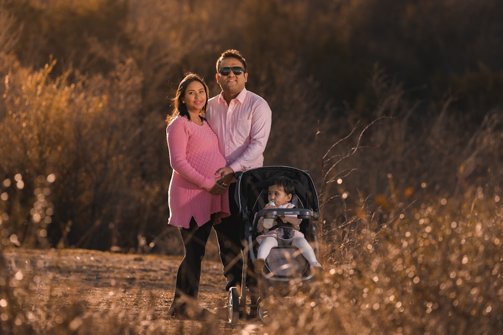 a man and a woman standing next to a baby in a stroller