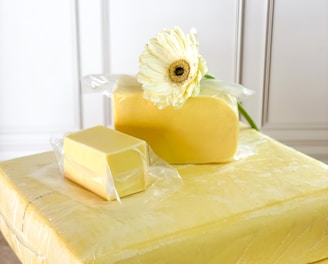 a piece of cheese sitting on top of a table next to a flower