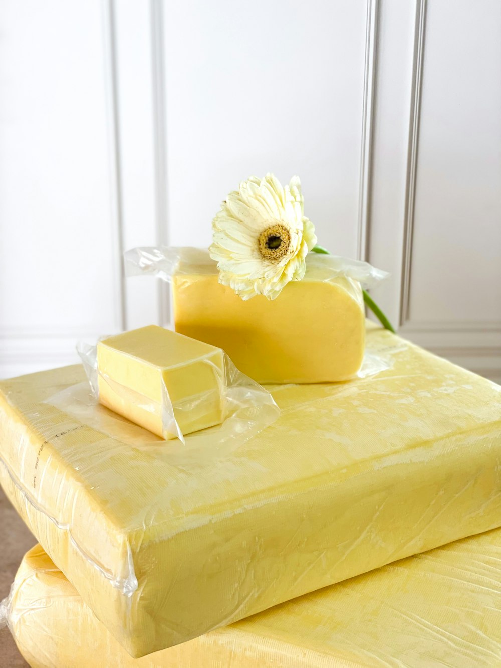 a piece of cheese sitting on top of a table next to a flower