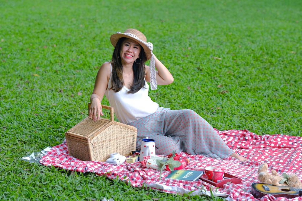 Una mujer sentada sobre una manta con una canasta de picnic