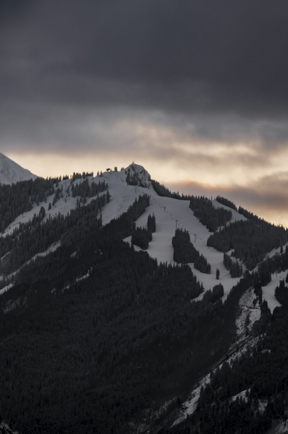 a mountain covered in snow under a cloudy sky