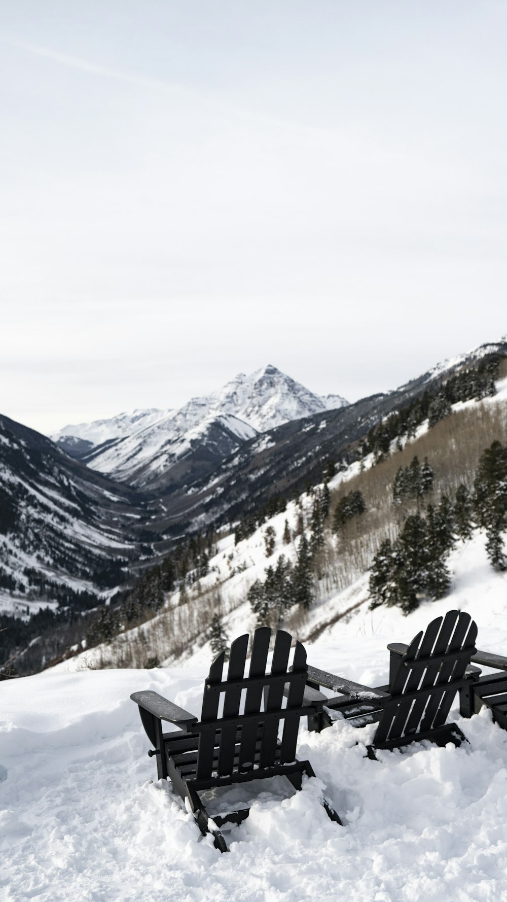 a couple of chairs sitting on top of a snow covered slope