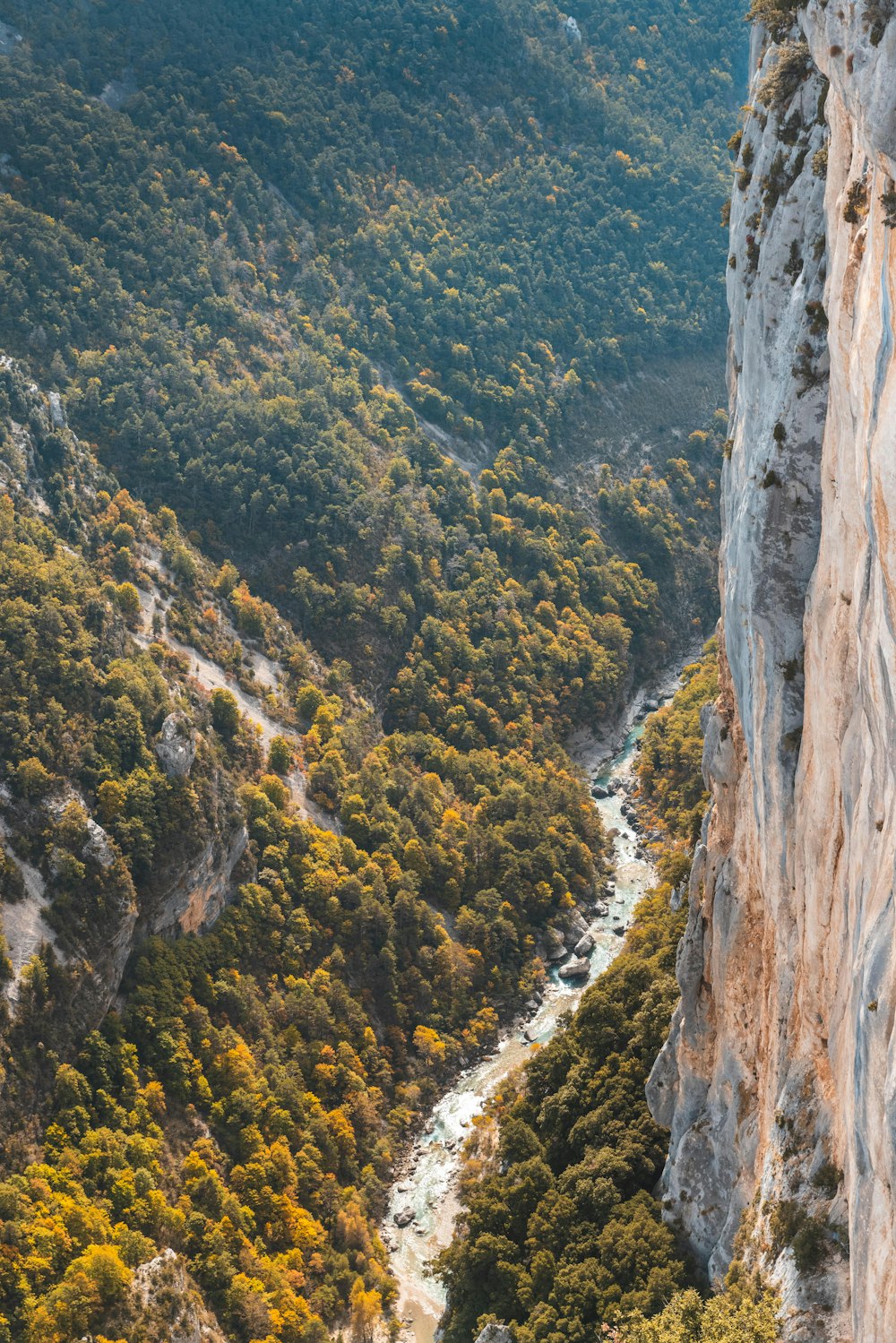 a man standing on the side of a cliff next to a river