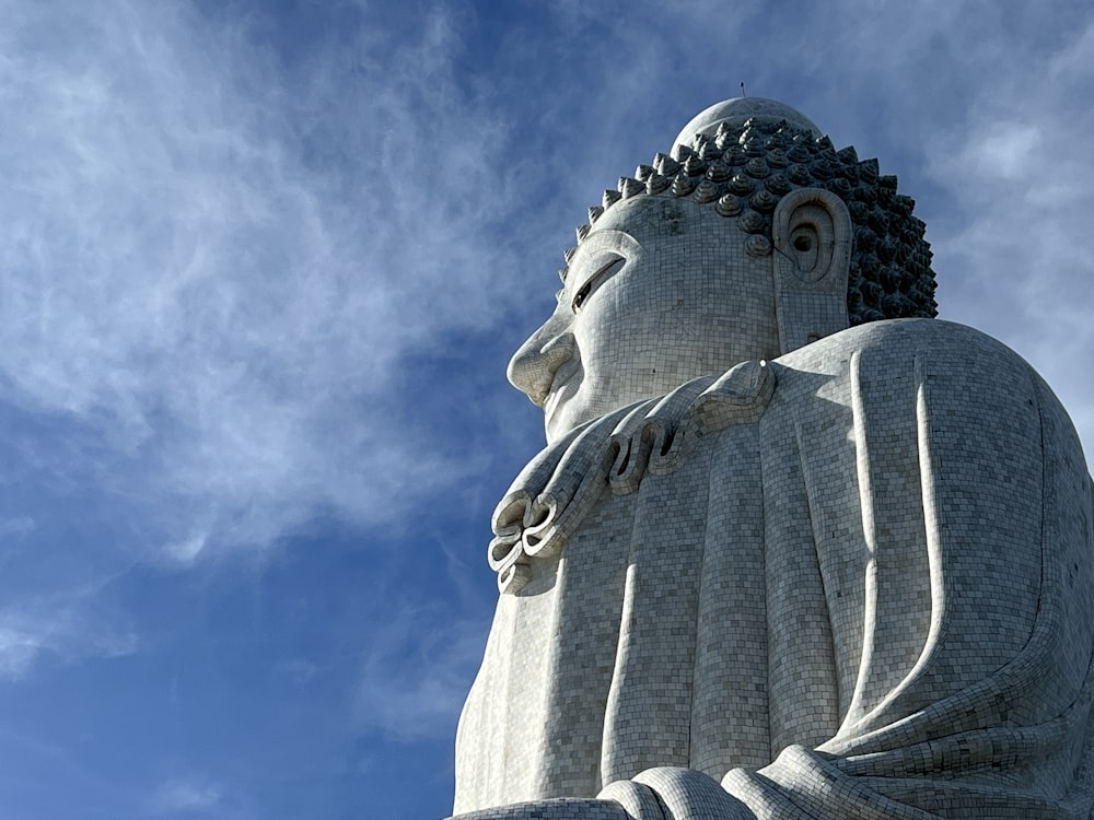 a large buddha statue sitting under a blue sky