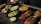 A variety of Indian dishes are arranged on a dark rustic table. The spread includes colorful and flavorful looking food, such as curries, grilled vegetables, and rice, garnished with fresh herbs.
