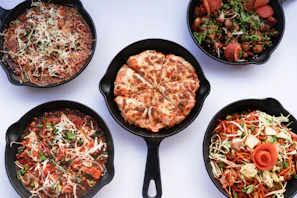 An array of side dishes including garlic bread, salads, and dipping sauces complementing the pizzas.