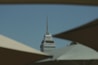 A tall, sharp-tipped skyscraper with the text 'Latino Seguros' is framed by dark shapes in the foreground against a clear blue sky.