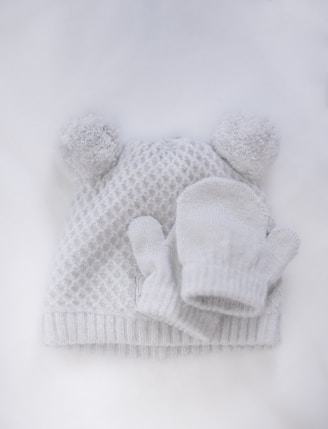 Flat-lay of a slouchy soft wool hat paired with gloves on a cozy knitted blanket.
