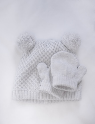 Flat-lay of a slouchy soft wool hat paired with gloves on a cozy knitted blanket.