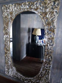 An ornate mirror with a detailed frame reflecting a tastefully decorated living room.