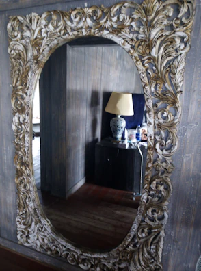 An ornate mirror with a detailed frame reflecting a tastefully decorated living room.