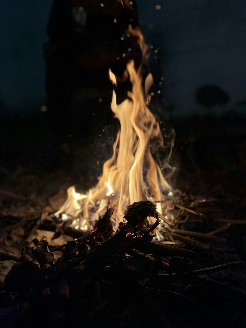 a person standing over a fire in the dark