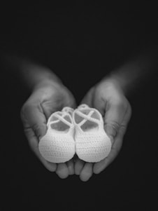 A warm, inviting scene of hands holding a pair of soft cotton slippers against a cozy home background.
