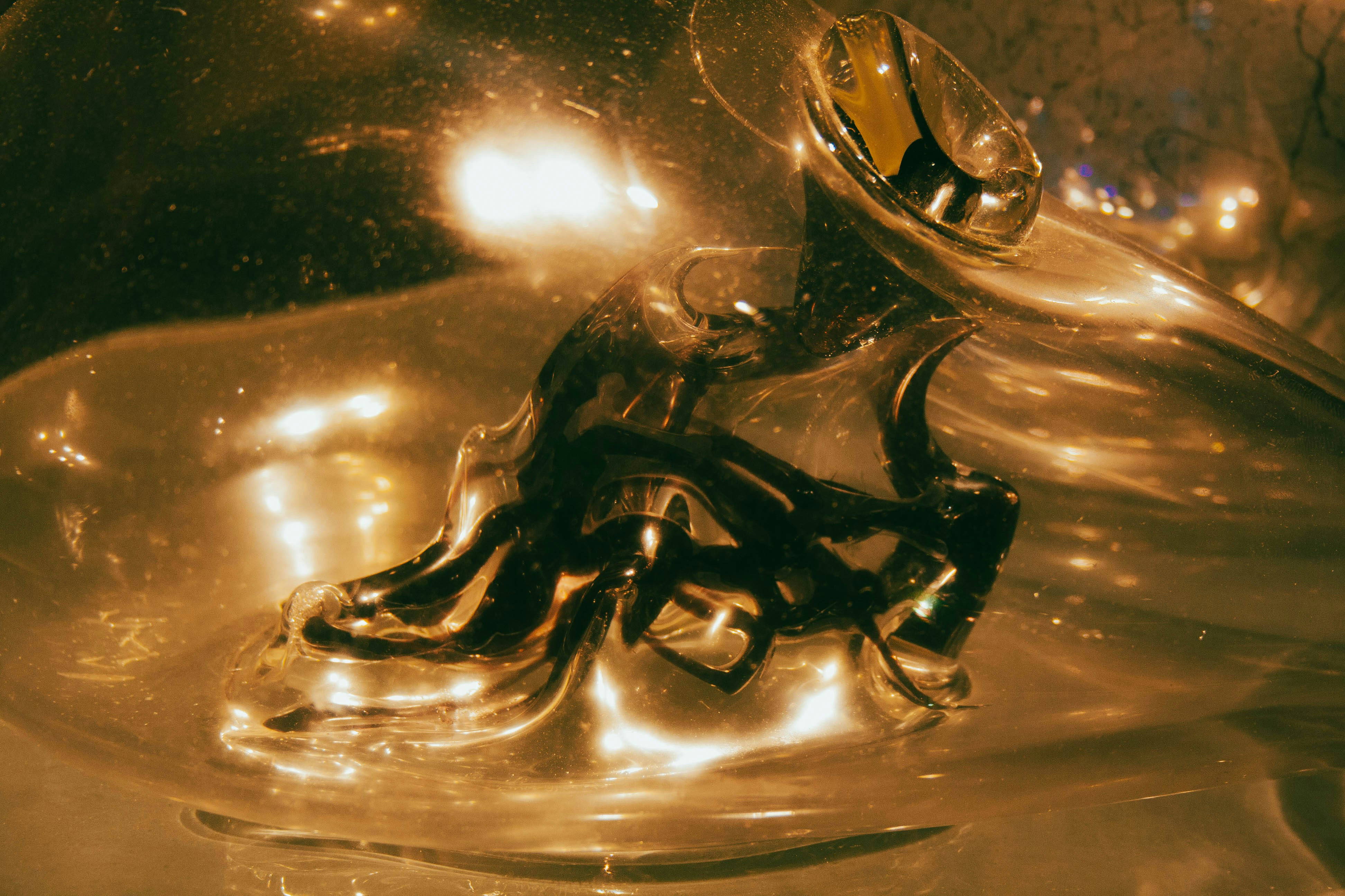 Sculpture abstraite en obsidienne noire avec des facettes géométriques reflétant la lumière dorée