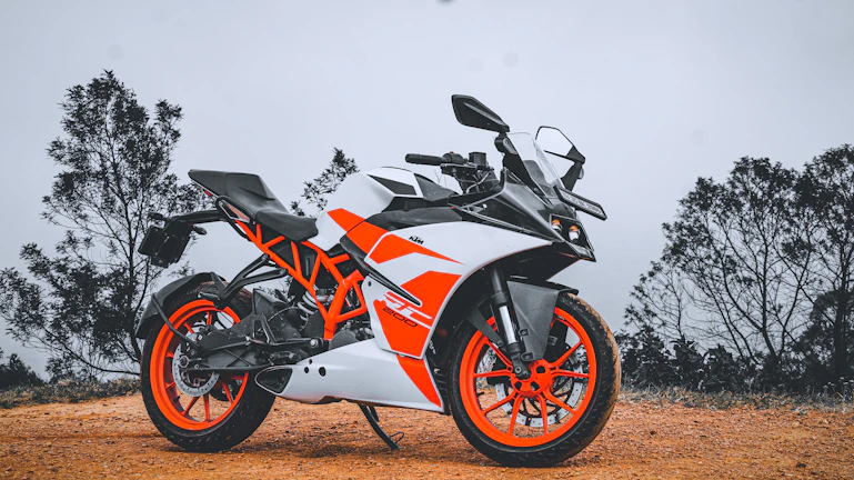 A vibrant orange-accented pitbike on a dirt track under a clear sky
