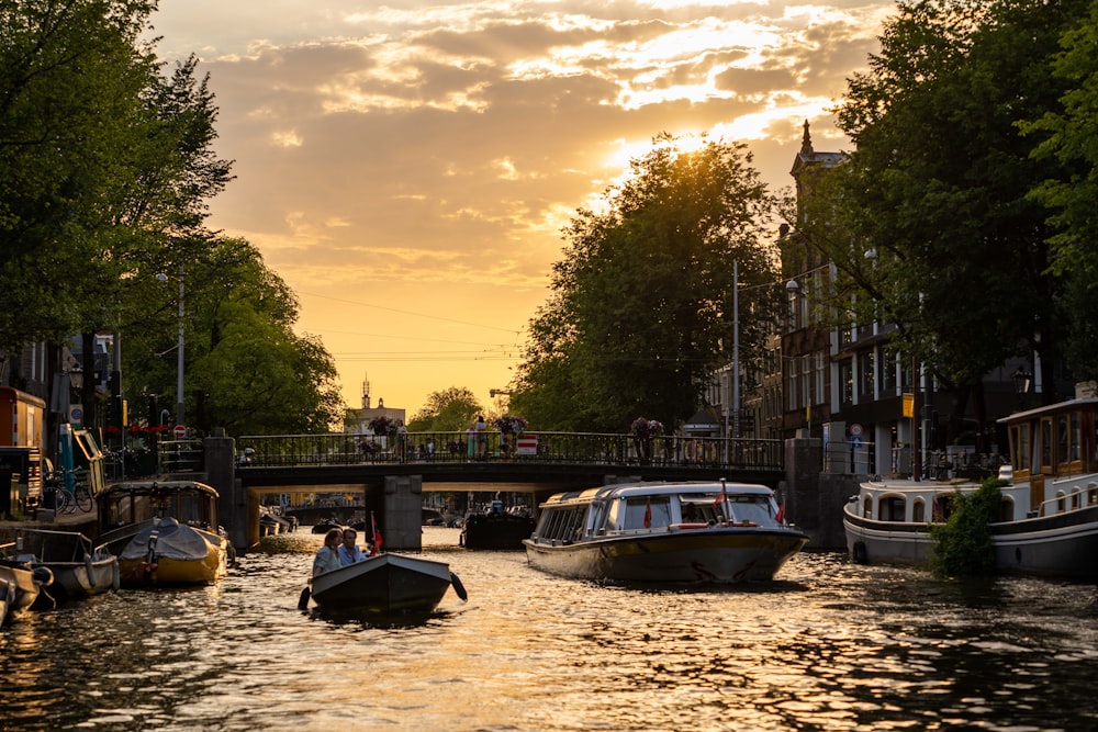 a group of boats floating down a river under a bridge