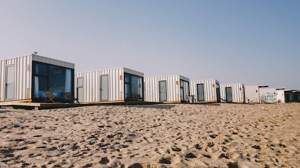 A sleek, modern portacabin installation site with workers assembling units under a clear blue sky.