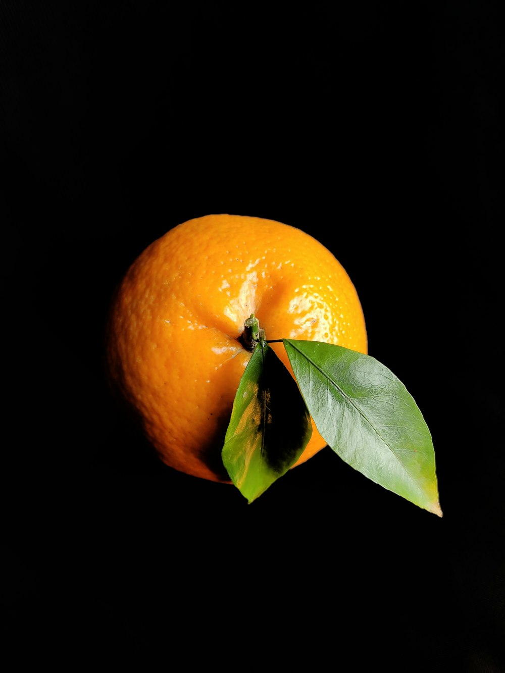 a close up of an orange with a leaf on it