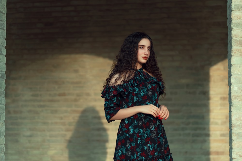 a woman standing in front of a brick wall