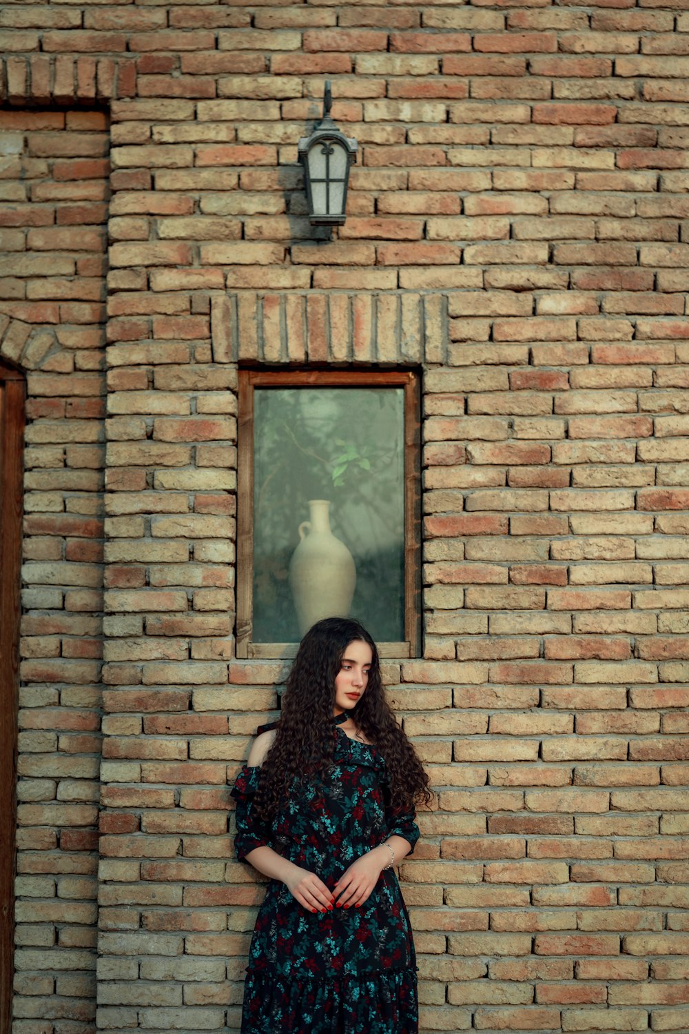 Una mujer parada frente a una pared de ladrillos