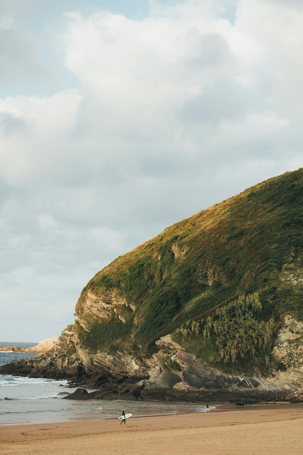 a couple of people walking on top of a sandy beach