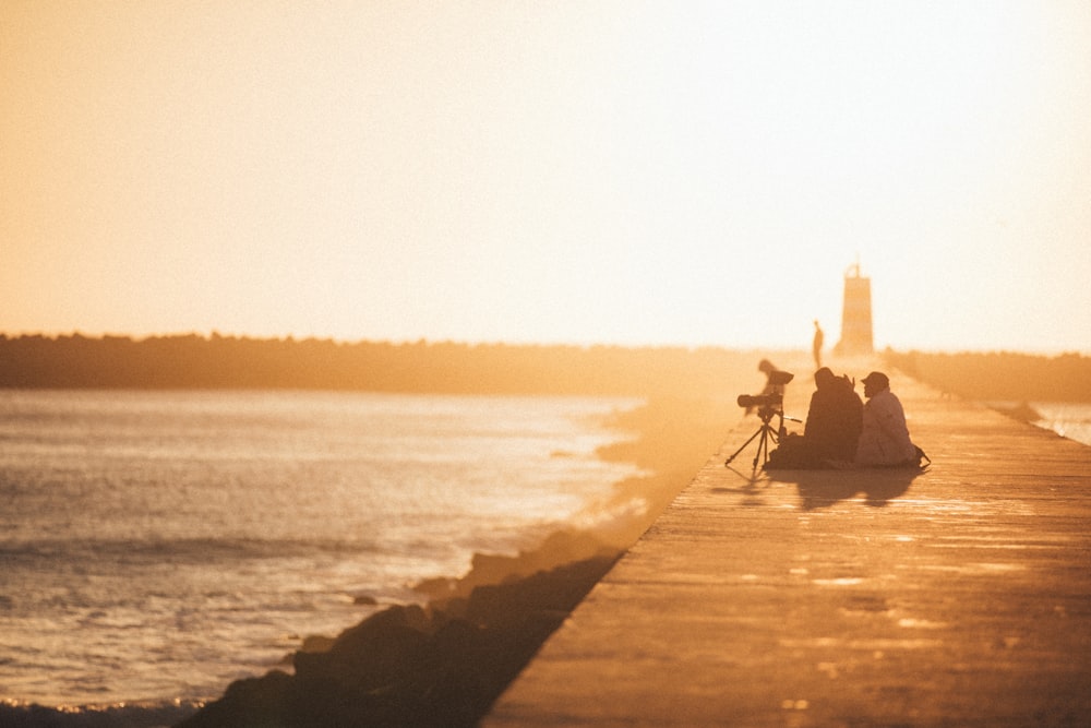 a couple of people that are sitting on a pier